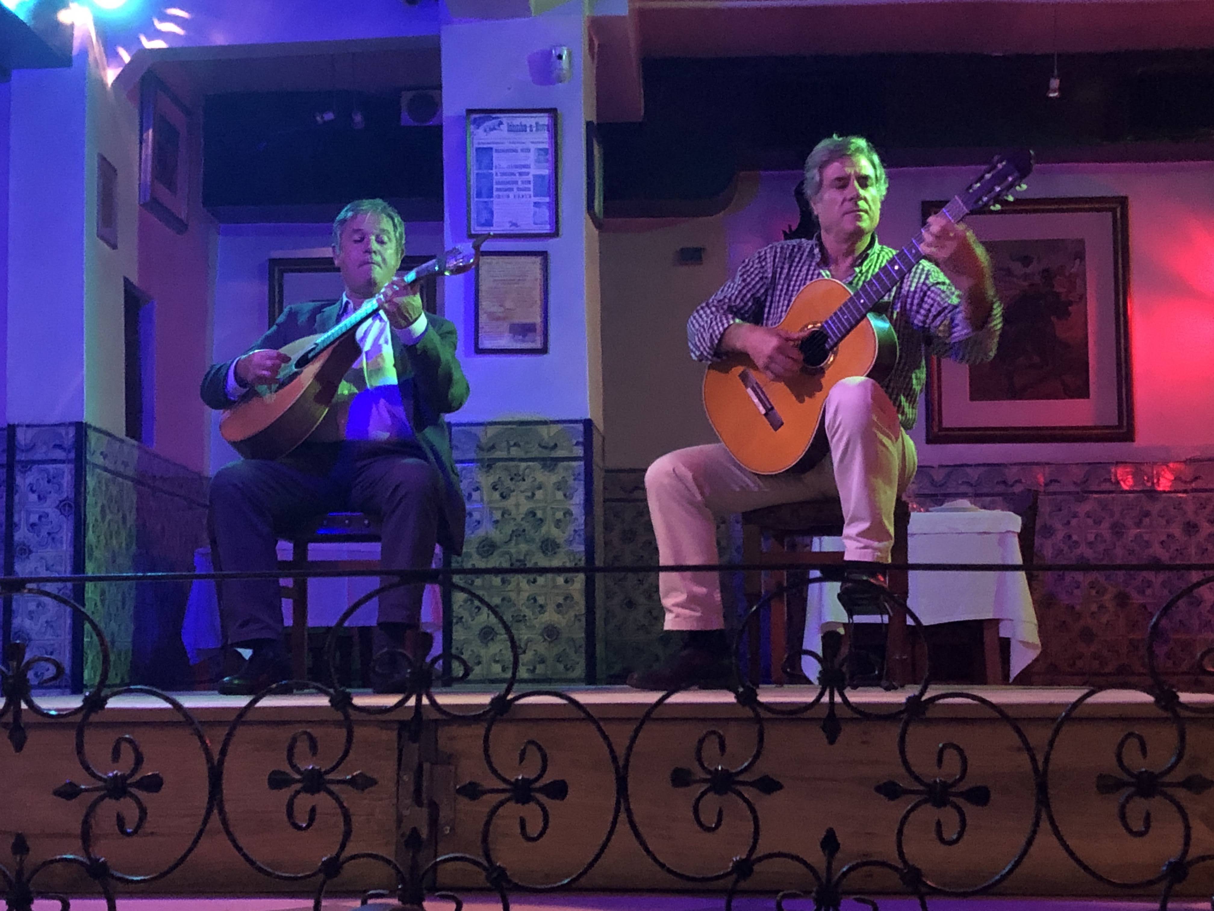 Two men playing guitars on a stage

AI-generated content may be incorrect.